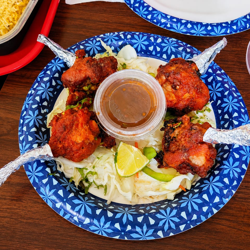 Four chicken lollipops with foil-wrapped bones, served on shredded cabbage with lime and dipping sauce.